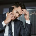 Stressed businessman on the phone, trading on the stock market during a financial crisis. Trader in