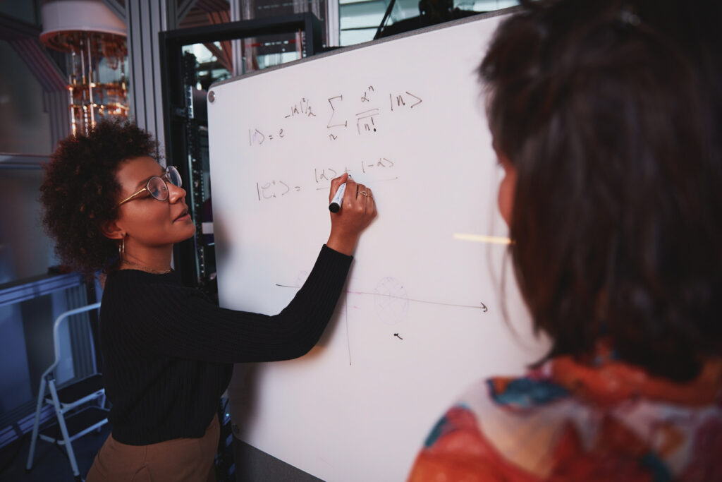 Researcher writing equations on a whiteboard at Alice & Bob