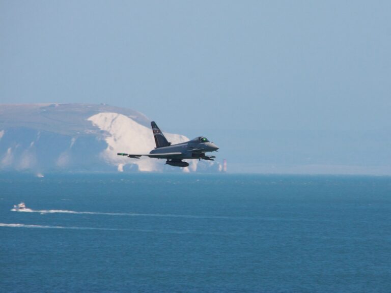 white and black jet plane flying over the sea during daytime