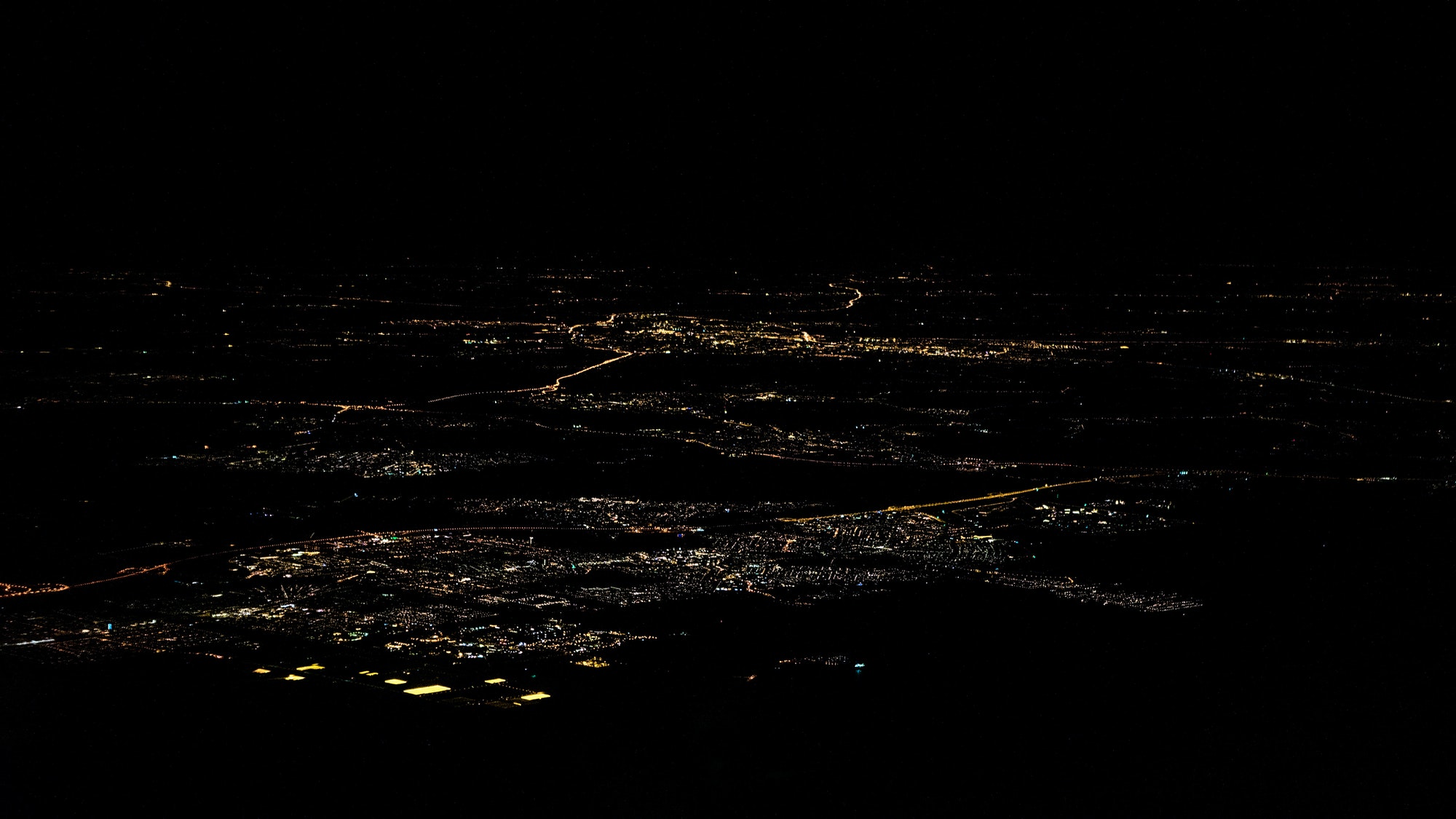 Lights of roads Amsterdam city top view from airplane window at night