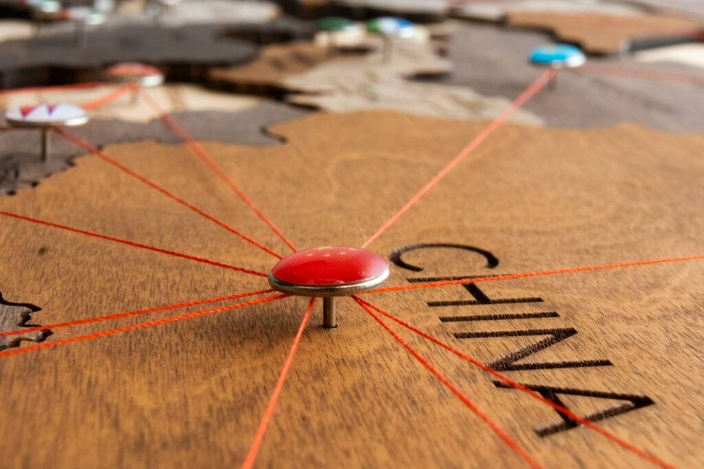 China flag on the pushpin and red threads on the wooden map