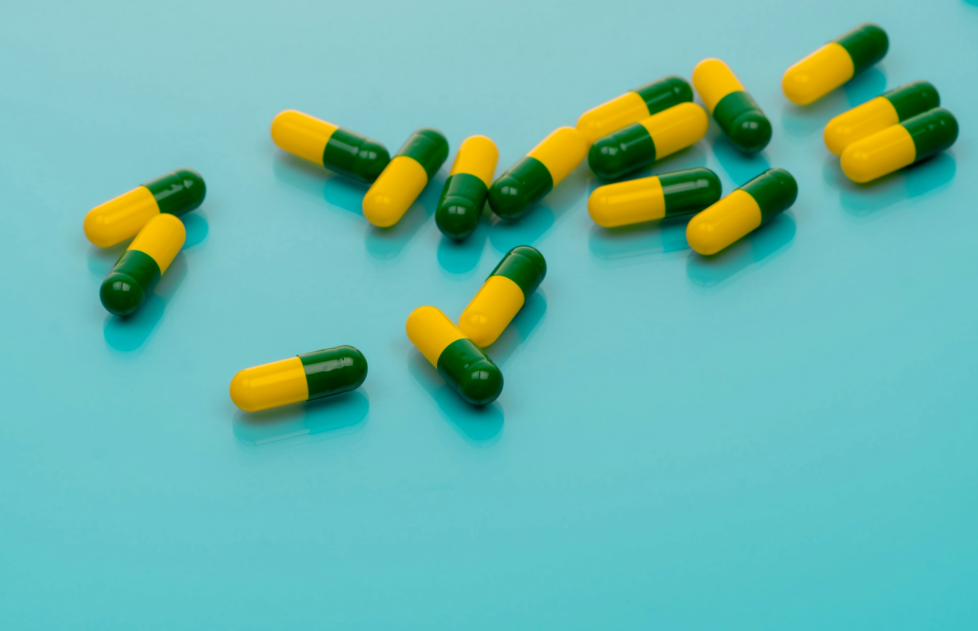 Green-yellow capsules spread on blue background. Tramadol capsule pills for relieve severe cancer