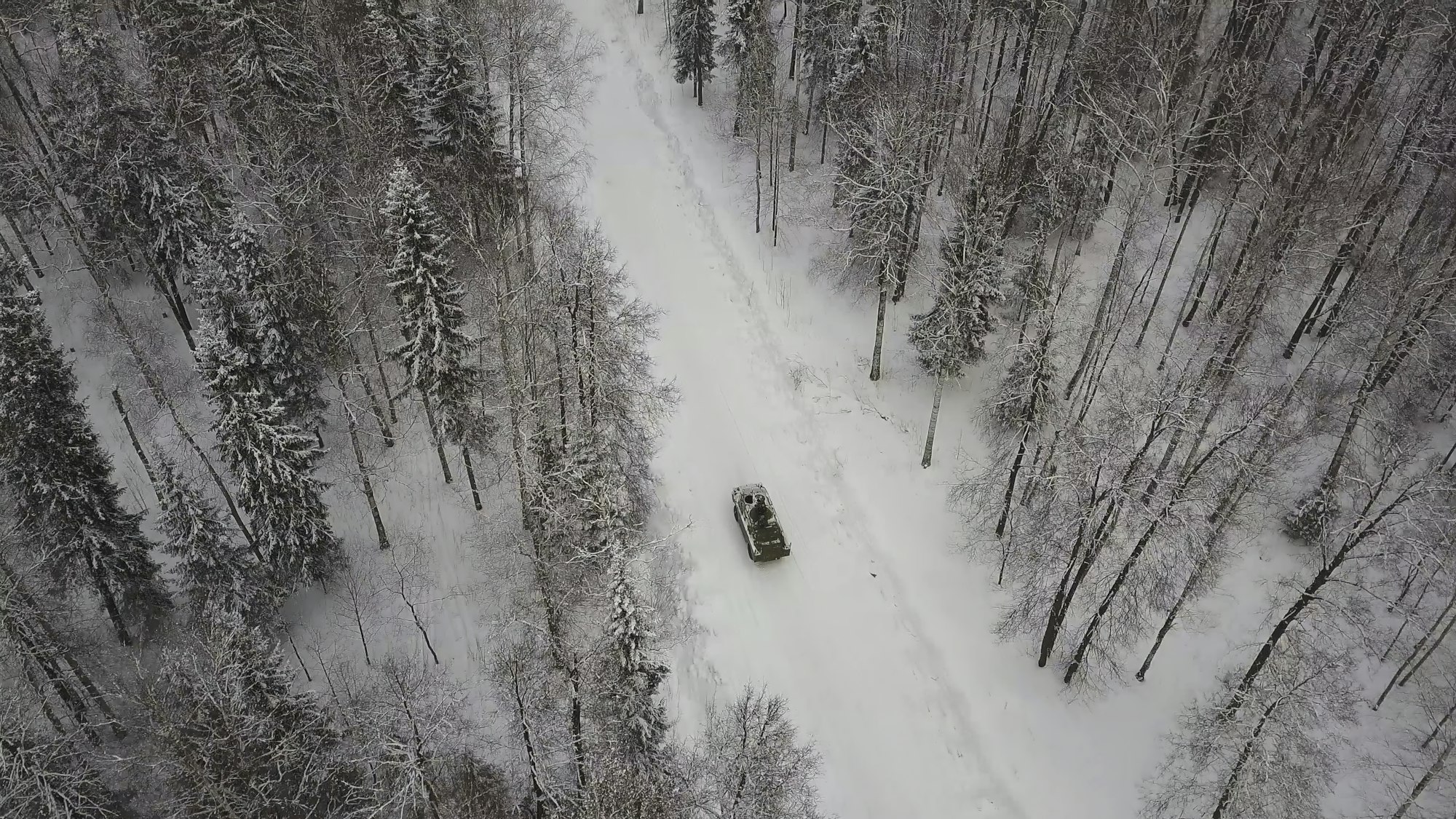 Aerial view of tank driving through the winter forest. Battle tank in the forest. Tank under the