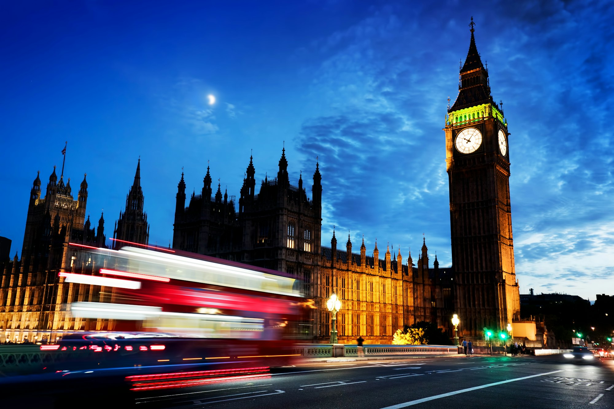 Red bus, Big Ben and Westminster Palace in London, the UK. at night. Moon shining