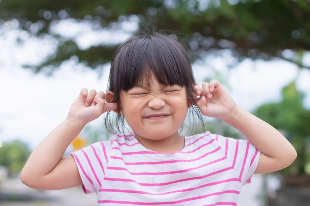 Portrait image of 4-5 years old kid. Close her ears and eyes.