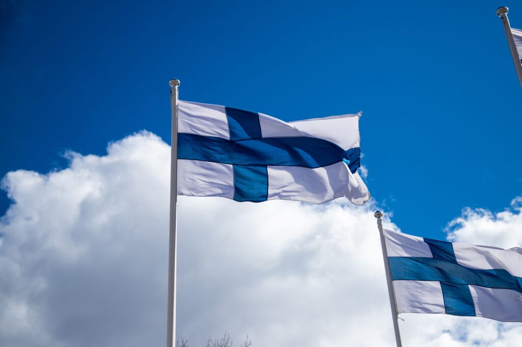 Finland flags waving on a flag pole in background of cloudy sky