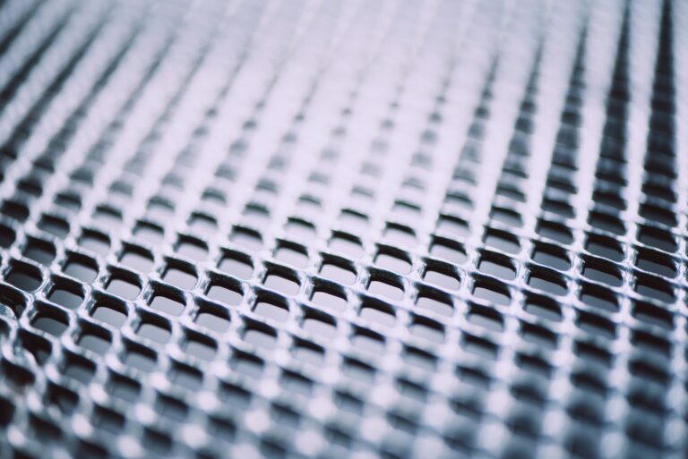 Metal background. Lattice texture with small cells grid. Selective focus point