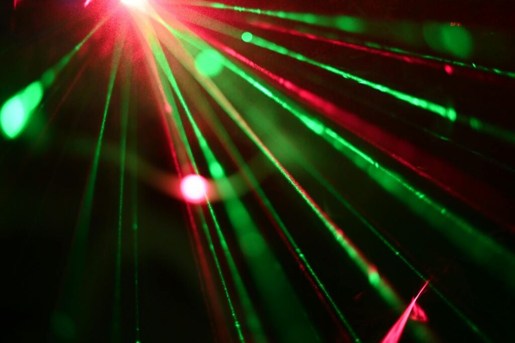Dynamic display of red and green laser lights creating vivid rays across a dark background.