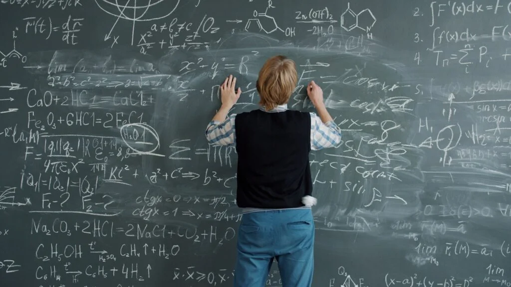 Student writing complex math equations on chalkboard