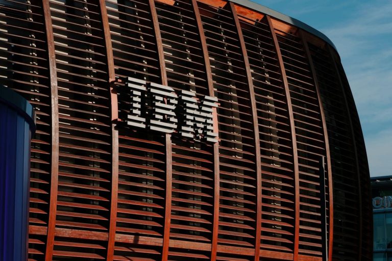 Close-up of IBM logo on a modern architectural facade under clear blue sky.