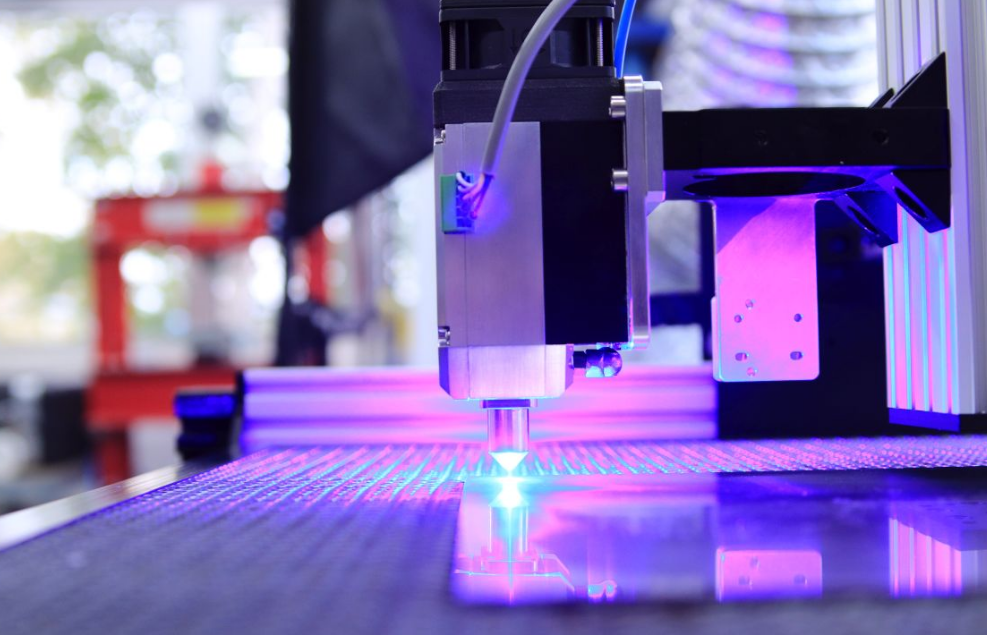 Close-up of a laser engraving machine working indoors with blue light reflection