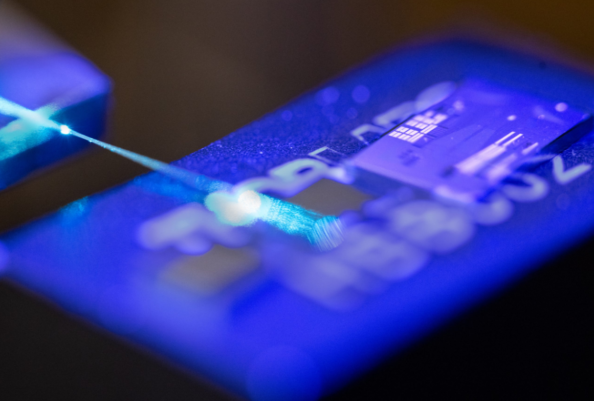 A laser illuminates the surface of a photonic integrated circuit at Sandia National Laboratories. (Photo by Craig Fritz)