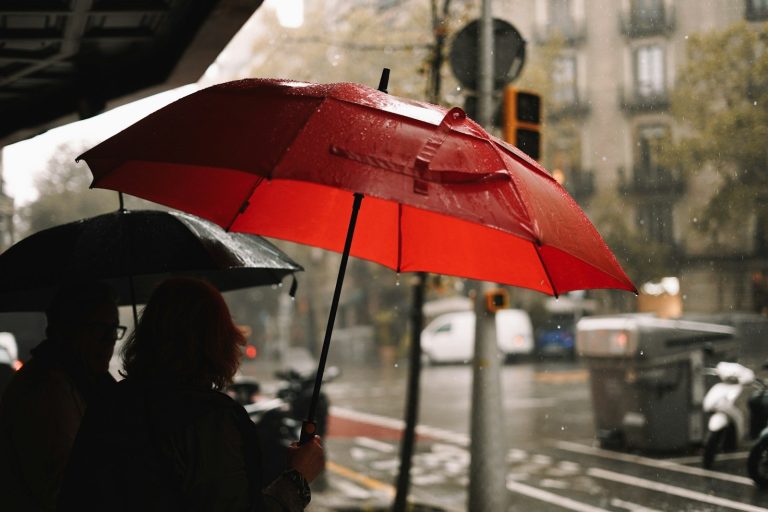 A person holding a red umbrella in the rain