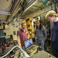 Dolev Bluvstein, Harry Levine (on the laptop), Sepehr Ebadi and Mikhail Lukin, on right, standing next to their neutral atom quantum computer, on left. Their new quantum processor can move atoms while preserving their quantum entanglement, enabling new types of computations where any two qubits can be entangled, even if they are far apart. (Image: Rose Lincoln/Harvard Staff Photographer)